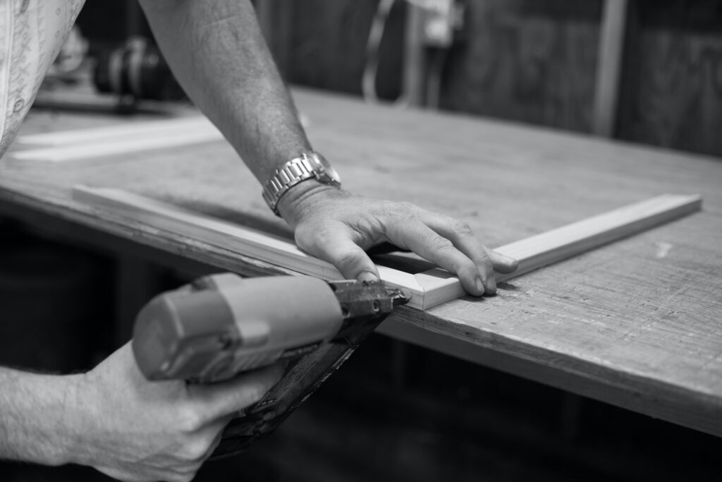 person using nail gun for wooden frame